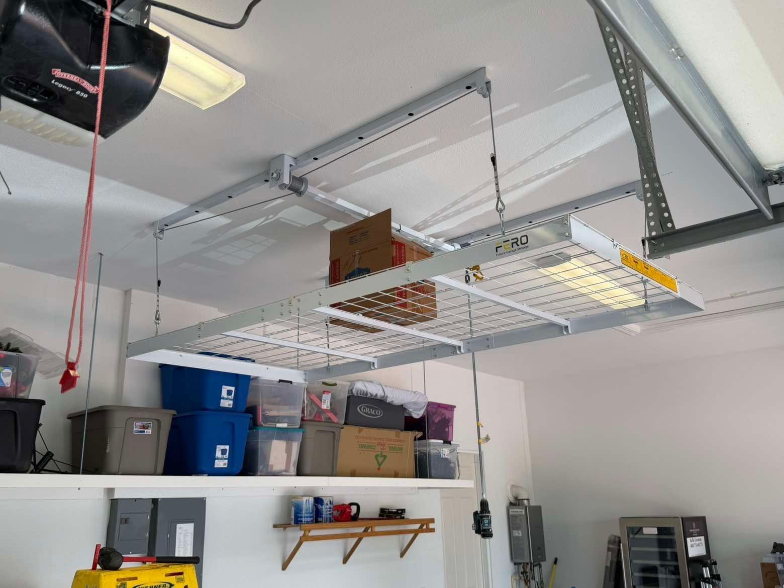 Garage ceiling storage racks with boxes and bins, plus shelves and tools along the wall.