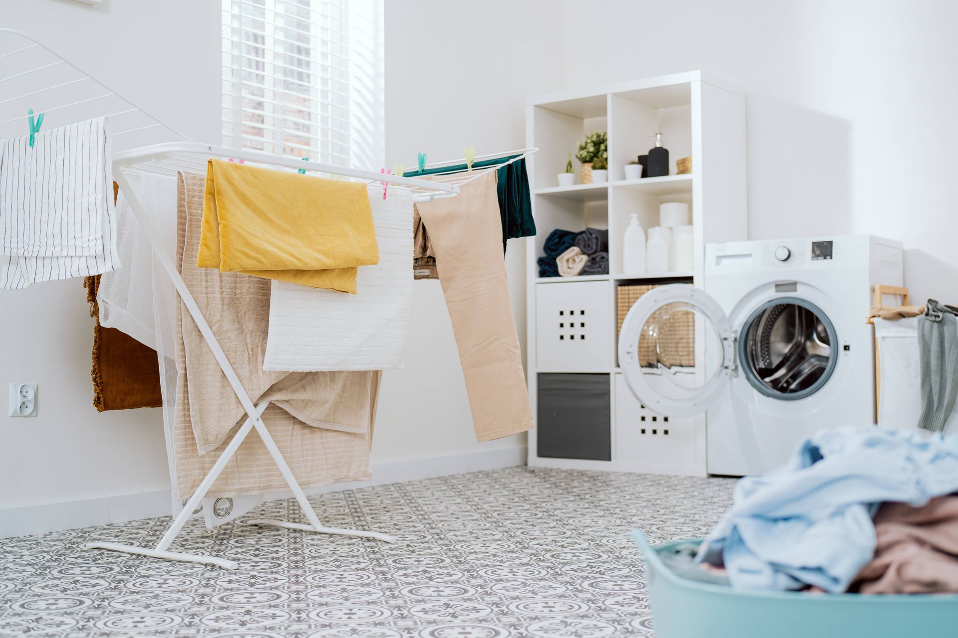 A busy laundry room with durable blinds on the window near the clothes line drying at Rachel Brosky 