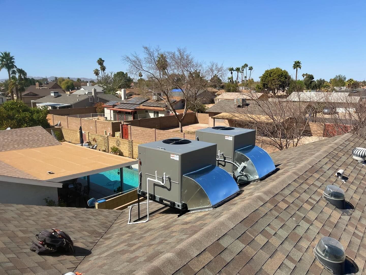 Two solar-powered HVAC units on a residential roof; sunny, suburban setting.