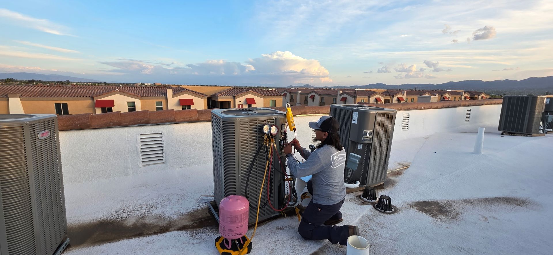 Air conditioner unit on wall, person working at desk near window.