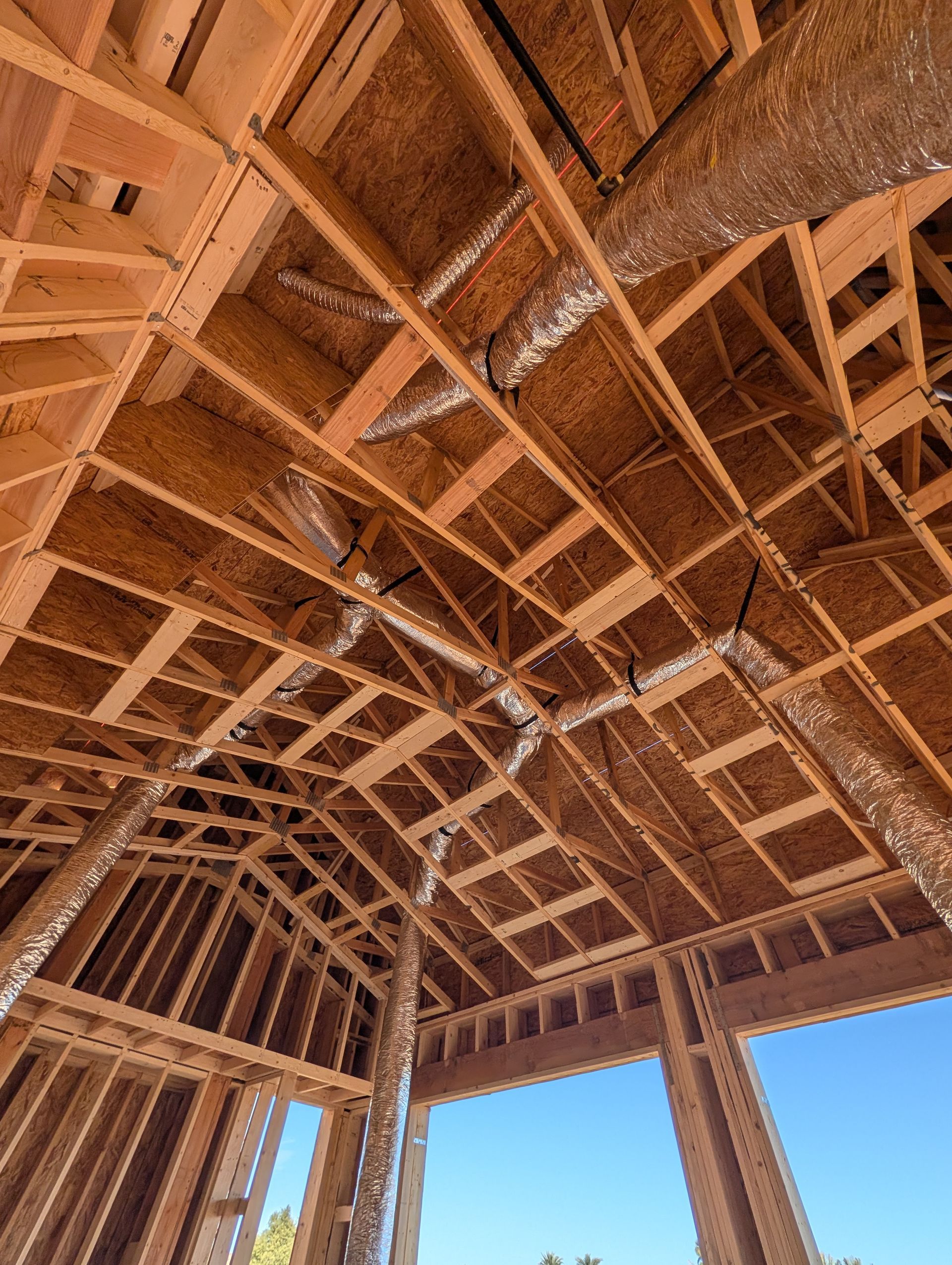 HVAC system installed in an attic framed with wooden beams, with flexible ductwork.