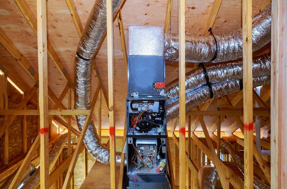 HVAC system installed in an attic framed with wooden beams, with flexible ductwork.