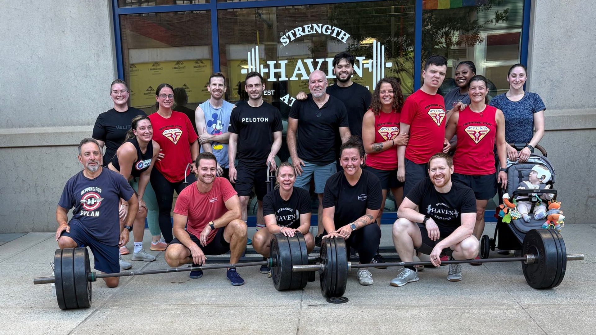 Group of people posing with two barbells in front of new haven gym