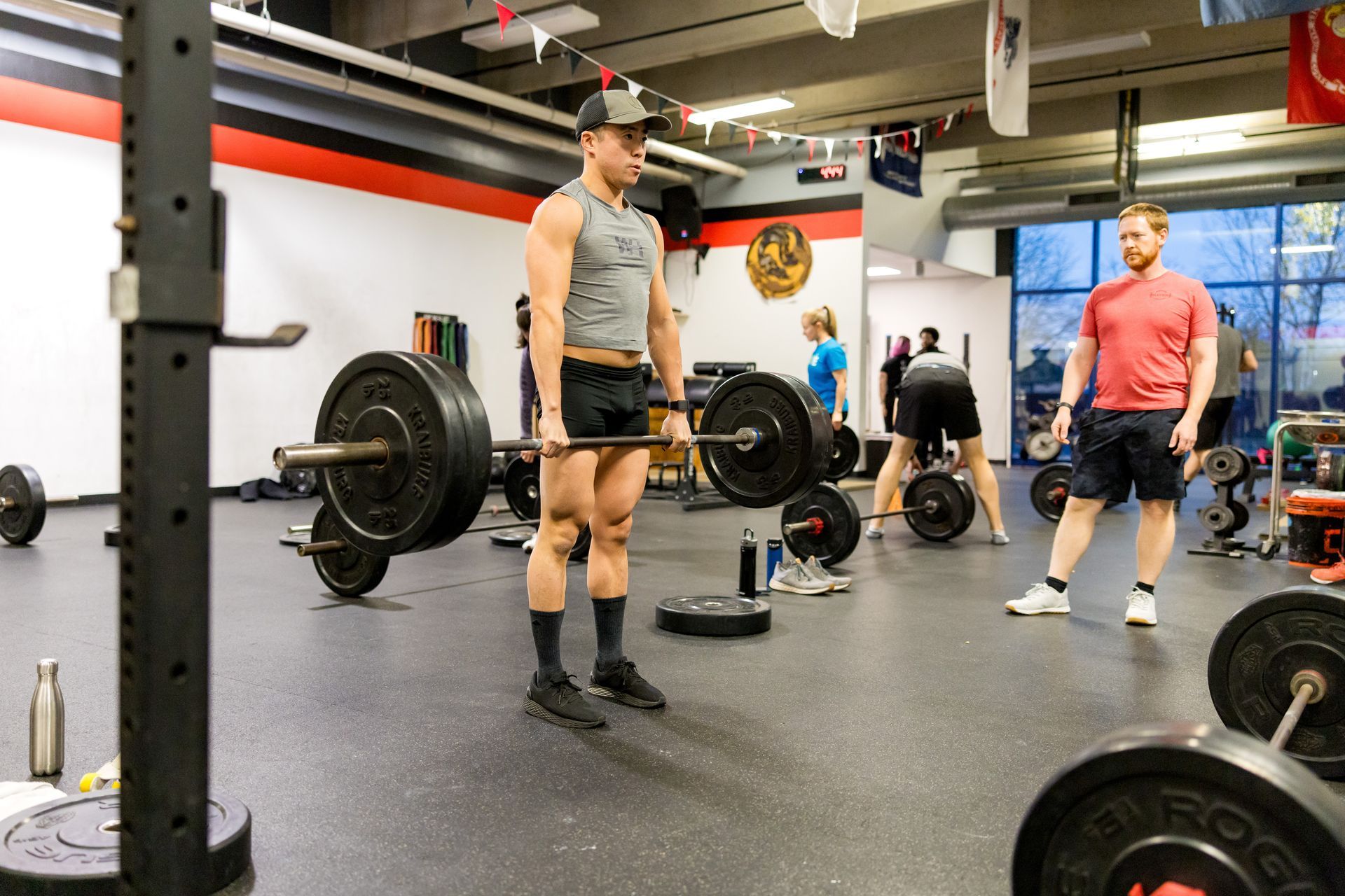 Man lifts barbell at Strength Haven Athletics; others exercising in background.