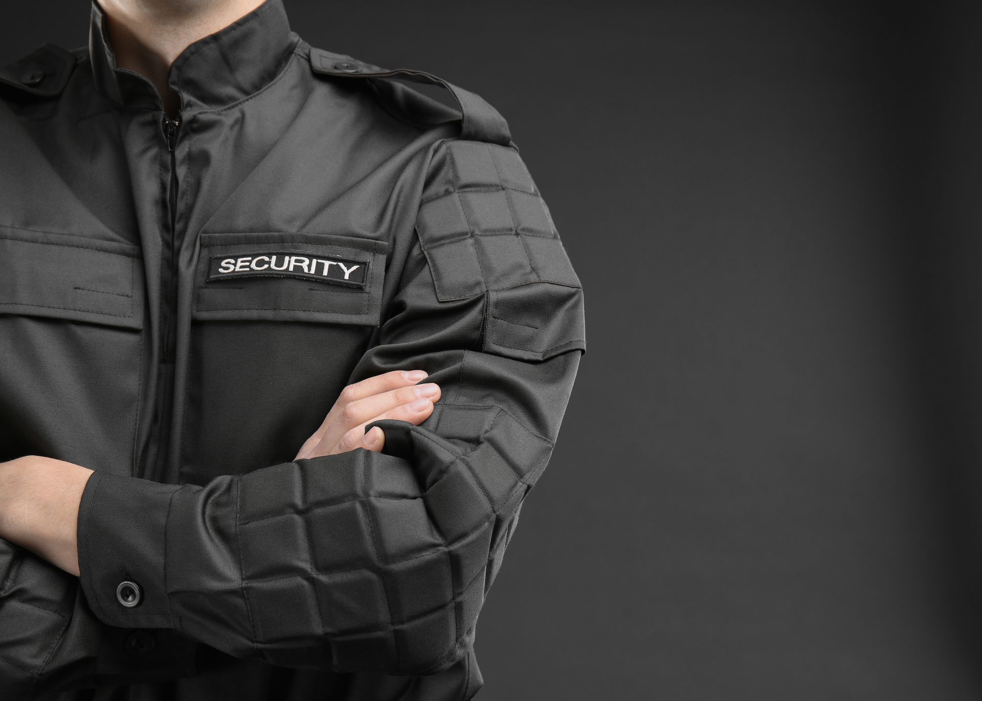 A security guard is standing with his arms crossed.