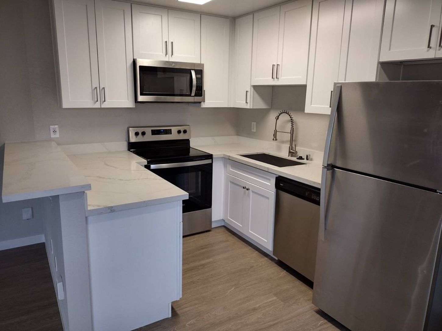 Modern kitchen with white cabinets, stainless steel appliances, and light countertops