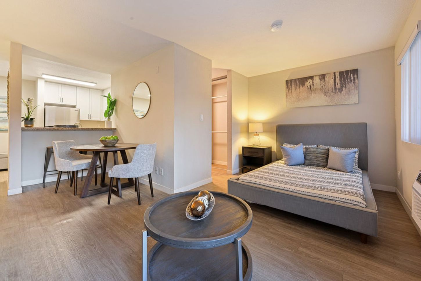 Modern studio apartment with bed, dining area, and kitchen in warm neutral tones