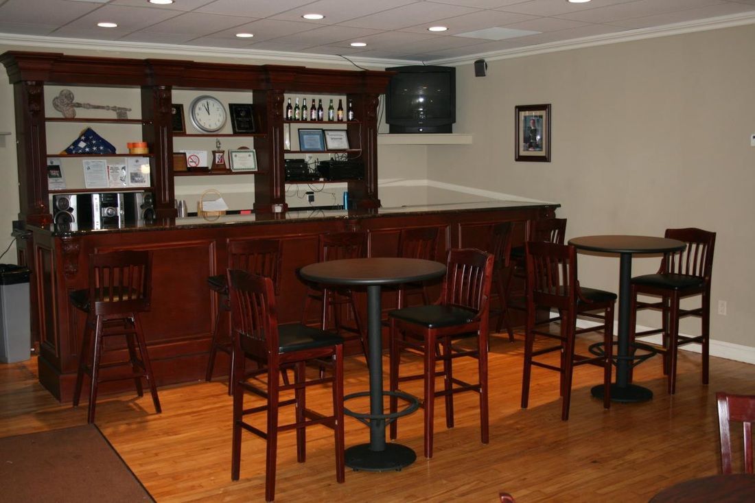 A room with tables and chairs in front of a bar
