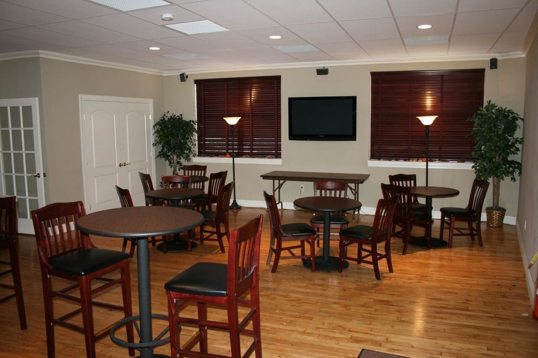 A room with tables and chairs and a flat screen tv