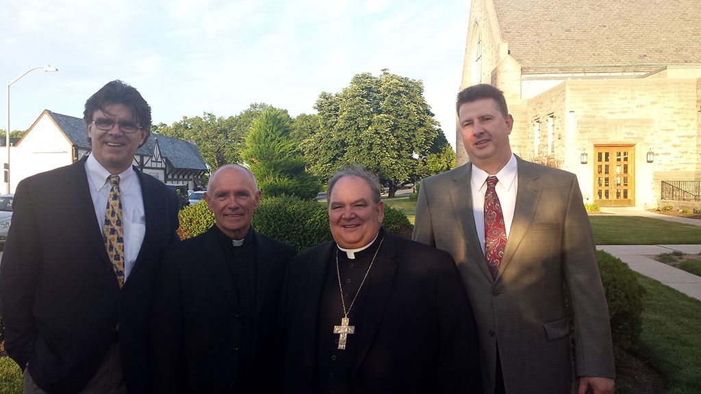 A group of men are posing for a picture in front of a church.