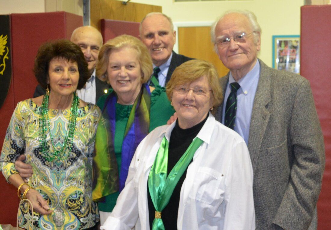 A group of people posing for a picture with one woman wearing a green scarf
