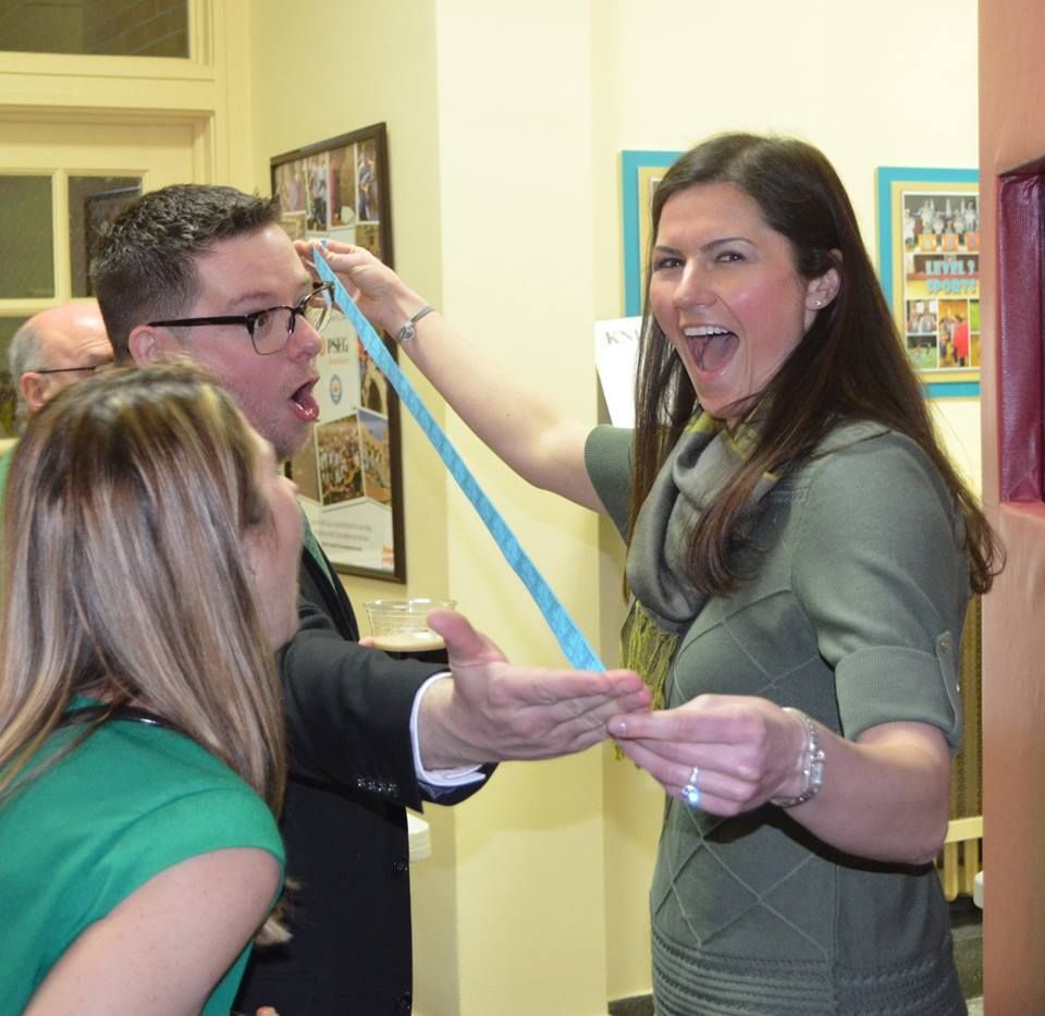 A man and two women are playing with a blue tape