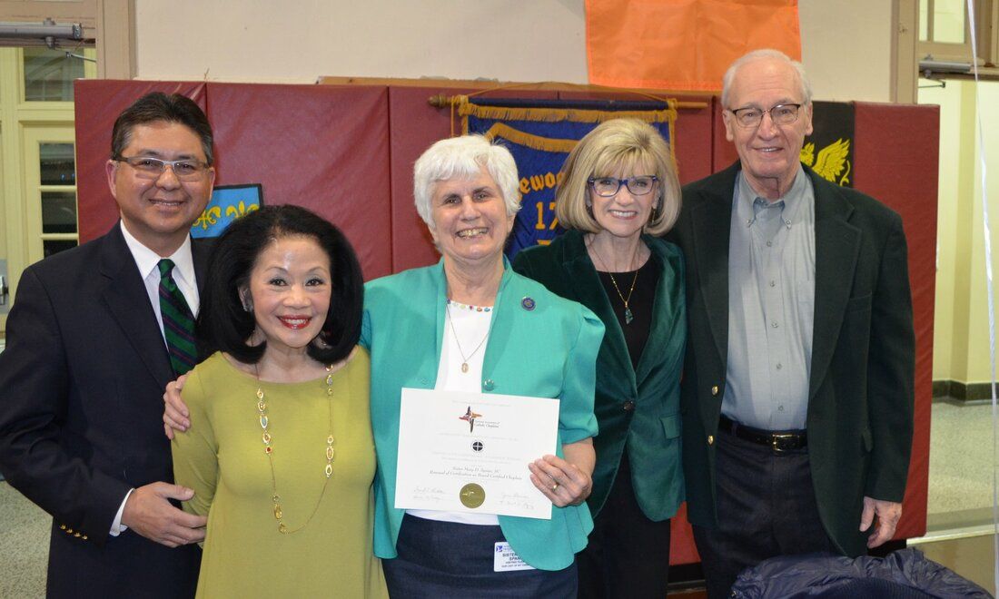 A group of people posing for a picture with one woman holding a certificate