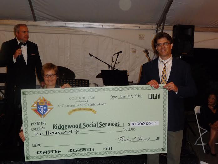 A man holding a check for ridgewood social services