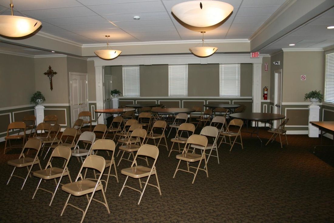 Rows of folding chairs in a room with a cross on the wall