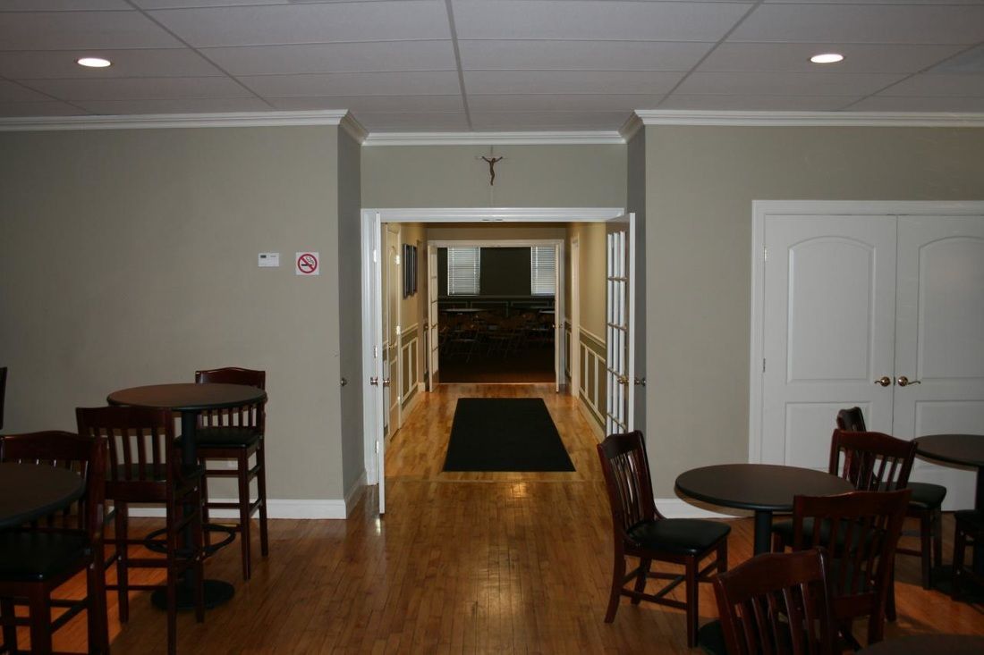 A hallway with tables and chairs and a cross on the ceiling