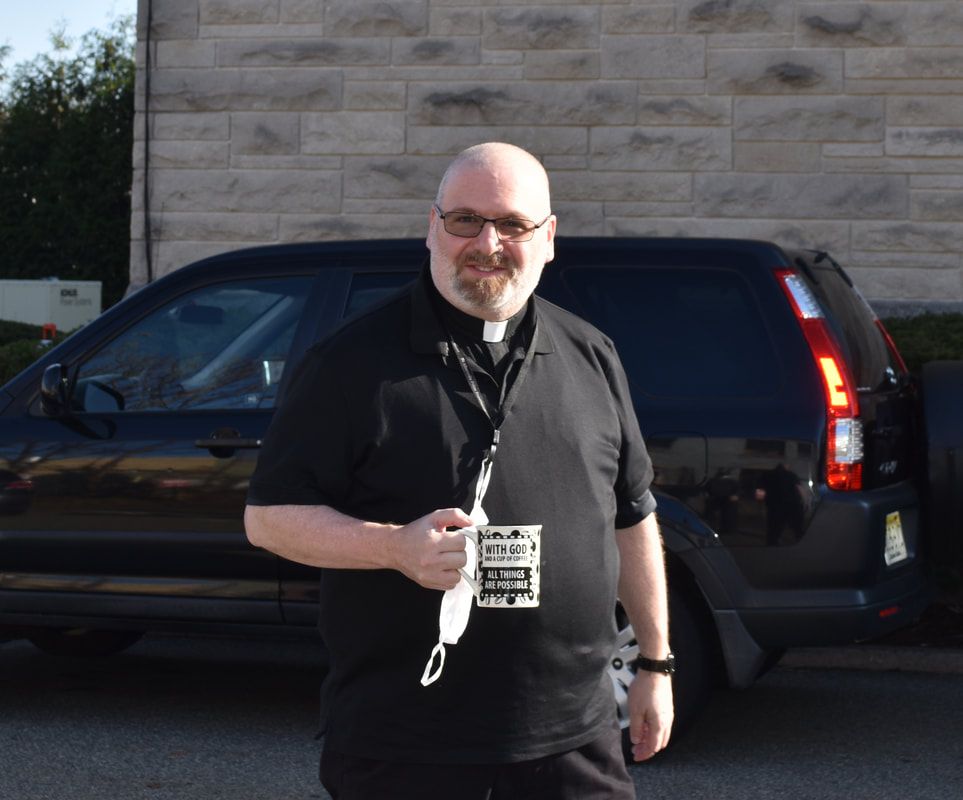 A man in a black shirt is standing in front of a black van