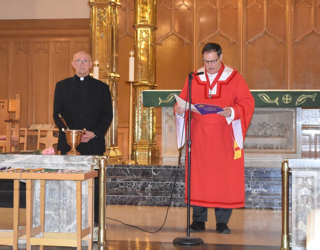 A man in a red robe is speaking into a microphone in a church