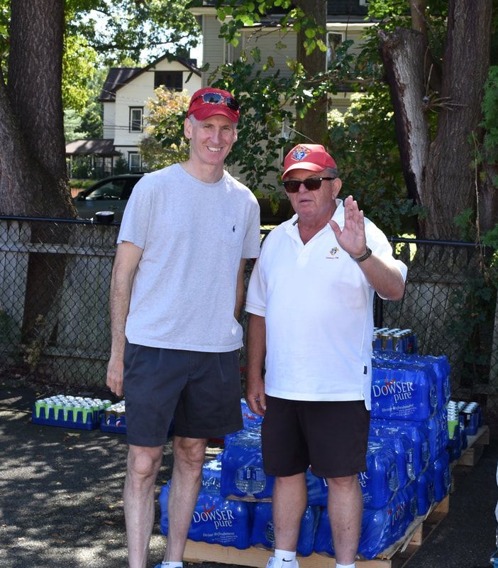 Two men standing in front of a stack of bottles of dasani water