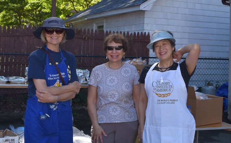 Three women are standing next to each other wearing aprons.