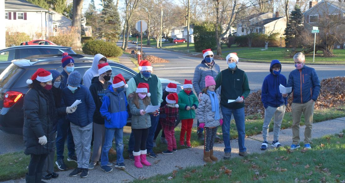 A group of people wearing santa hats are standing on a sidewalk.