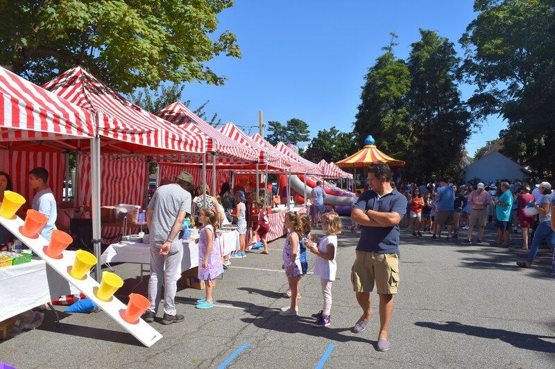 A group of people are standing in a parking lot at a carnival.