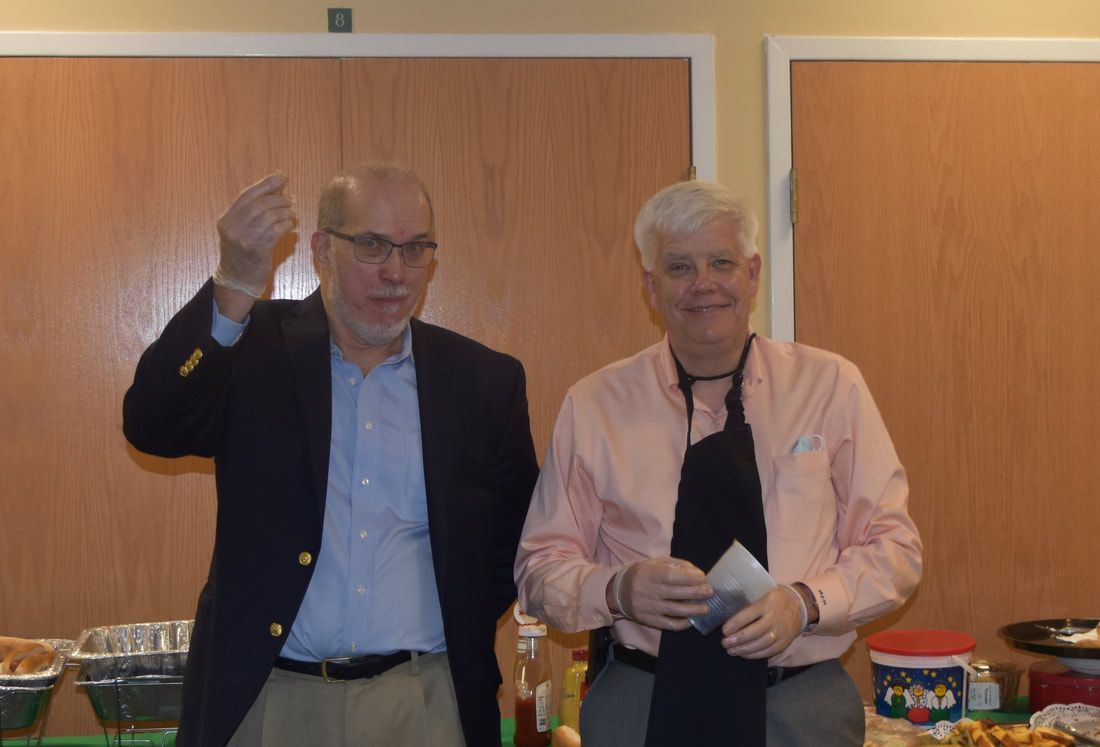Two men are standing next to each other in front of a buffet table.
