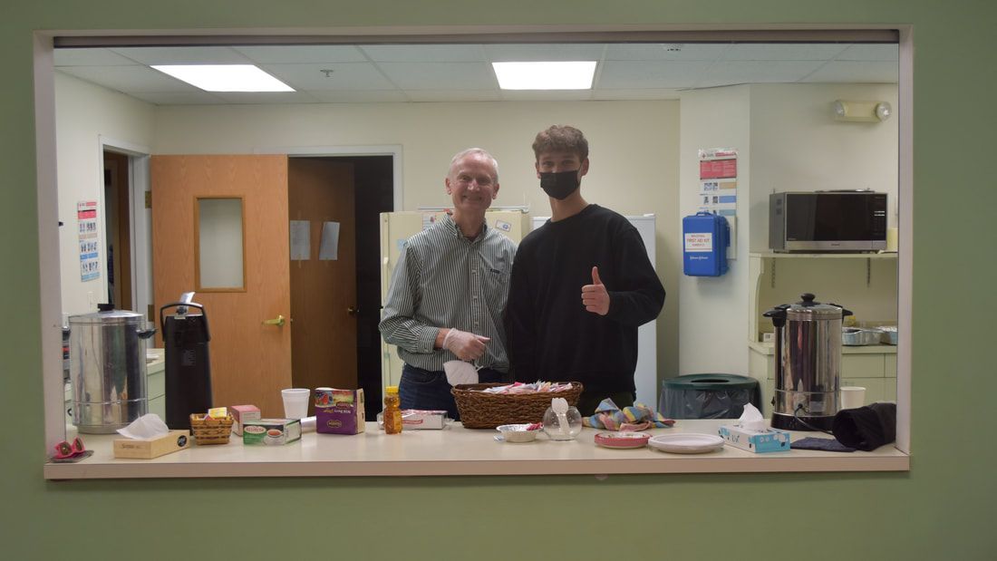 Two men are standing in a kitchen giving a thumbs up.