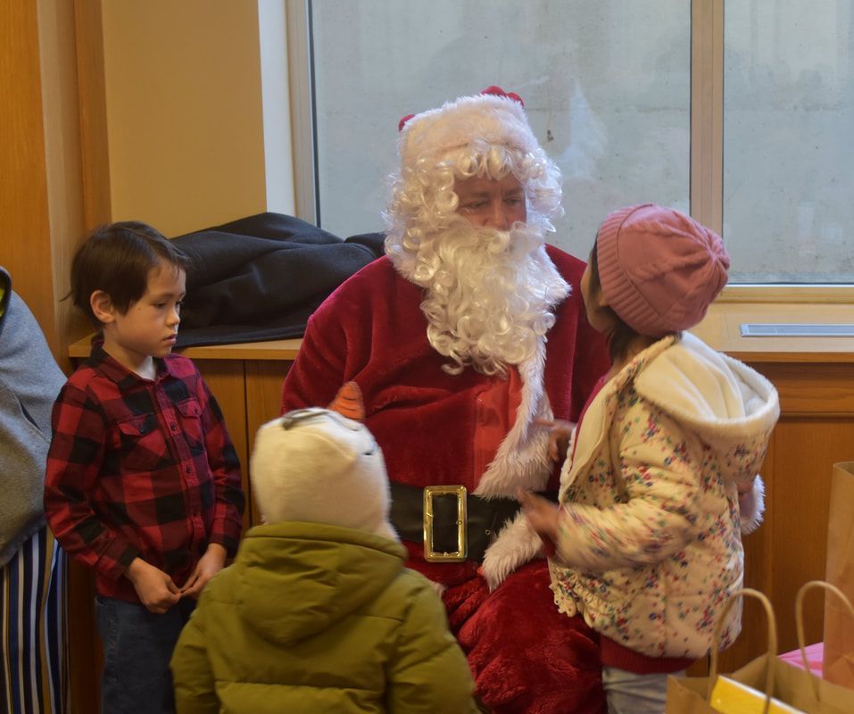 A group of children are standing around a man dressed as santa claus