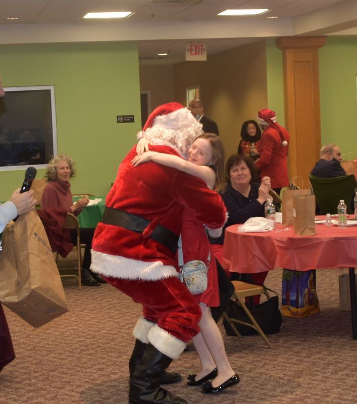A man in a santa suit is hugging a little girl
