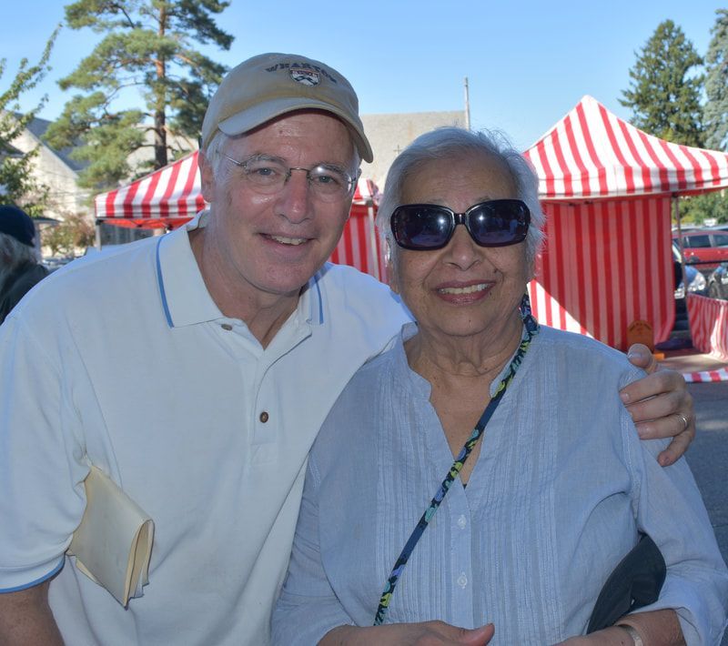 A man and woman posing for a picture in front of striped tents