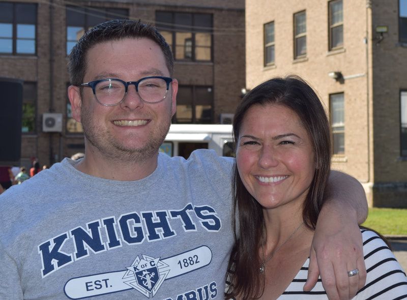 A man and woman are posing for a picture and the man is wearing a knights shirt