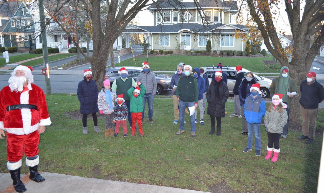A group of people wearing santa hats are standing in front of a house