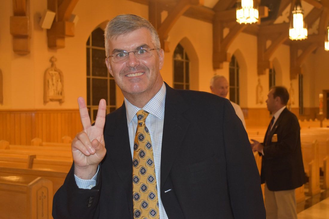 A man in a suit and tie is giving a peace sign