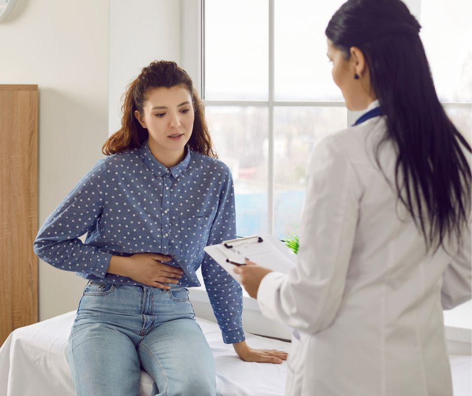 Person in a consultation, holding their stomach, discussing UTI symptoms.