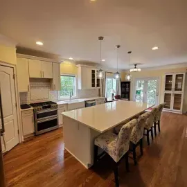 Bright kitchen with white cabinetry, a large central island, stainless steel appliances, and wood floors.
