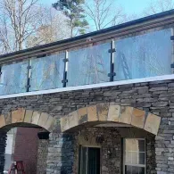 A stone facade building with arched entryways and a glass balcony railing on the upper level.