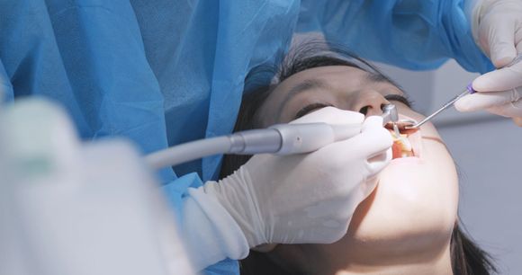 Dentista che usa uno strumento nella bocca aperta di un paziente durante una procedura odontoiatrica