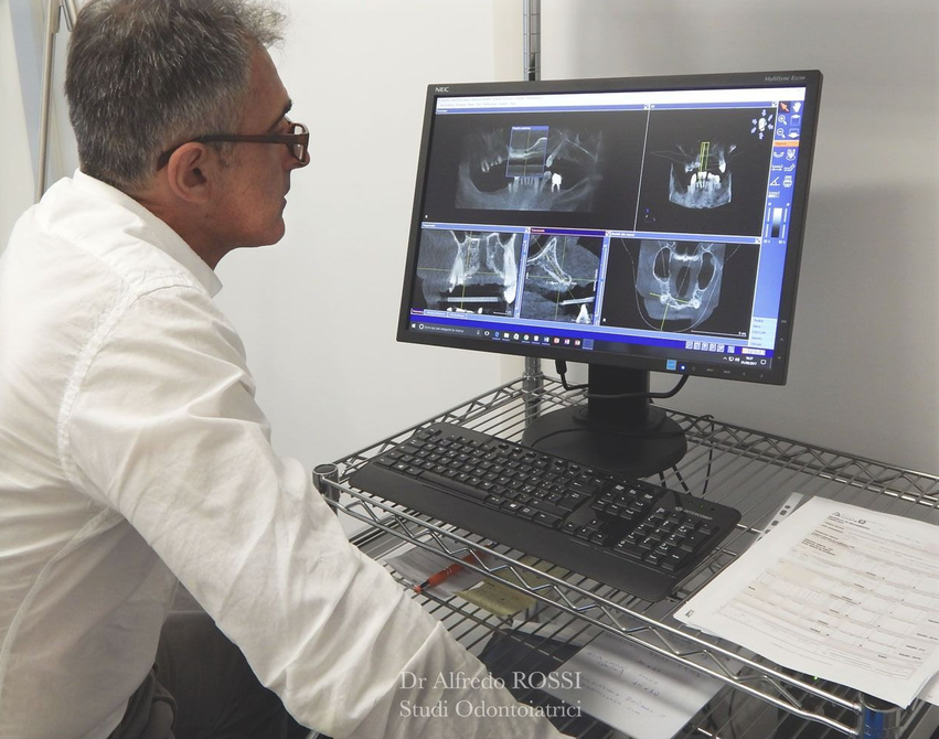 Medico che esamina immagini diagnostiche su un monitor desktop in uno studio medico