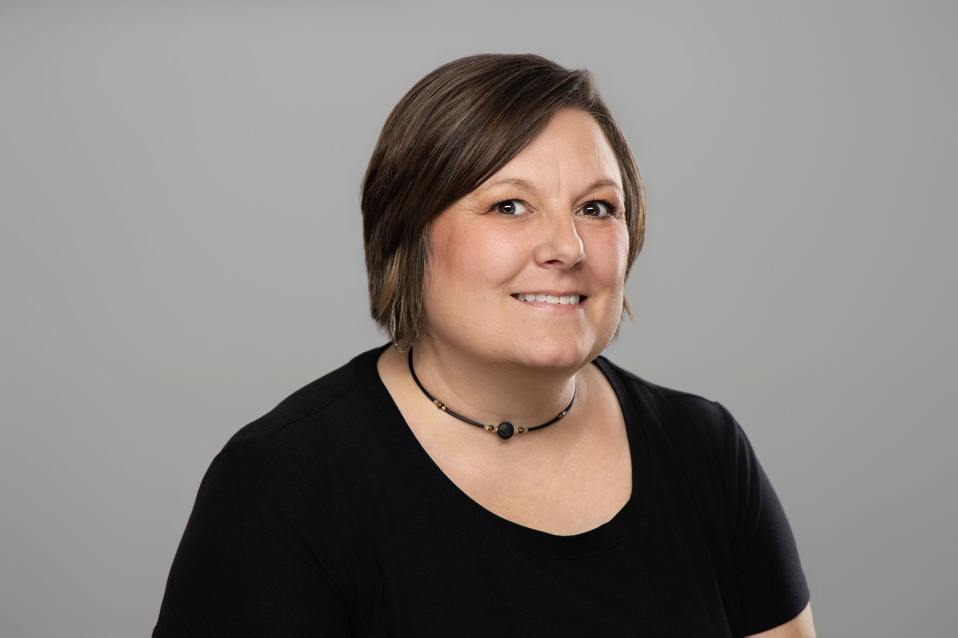 Smiling woman in a black top against a light gray background