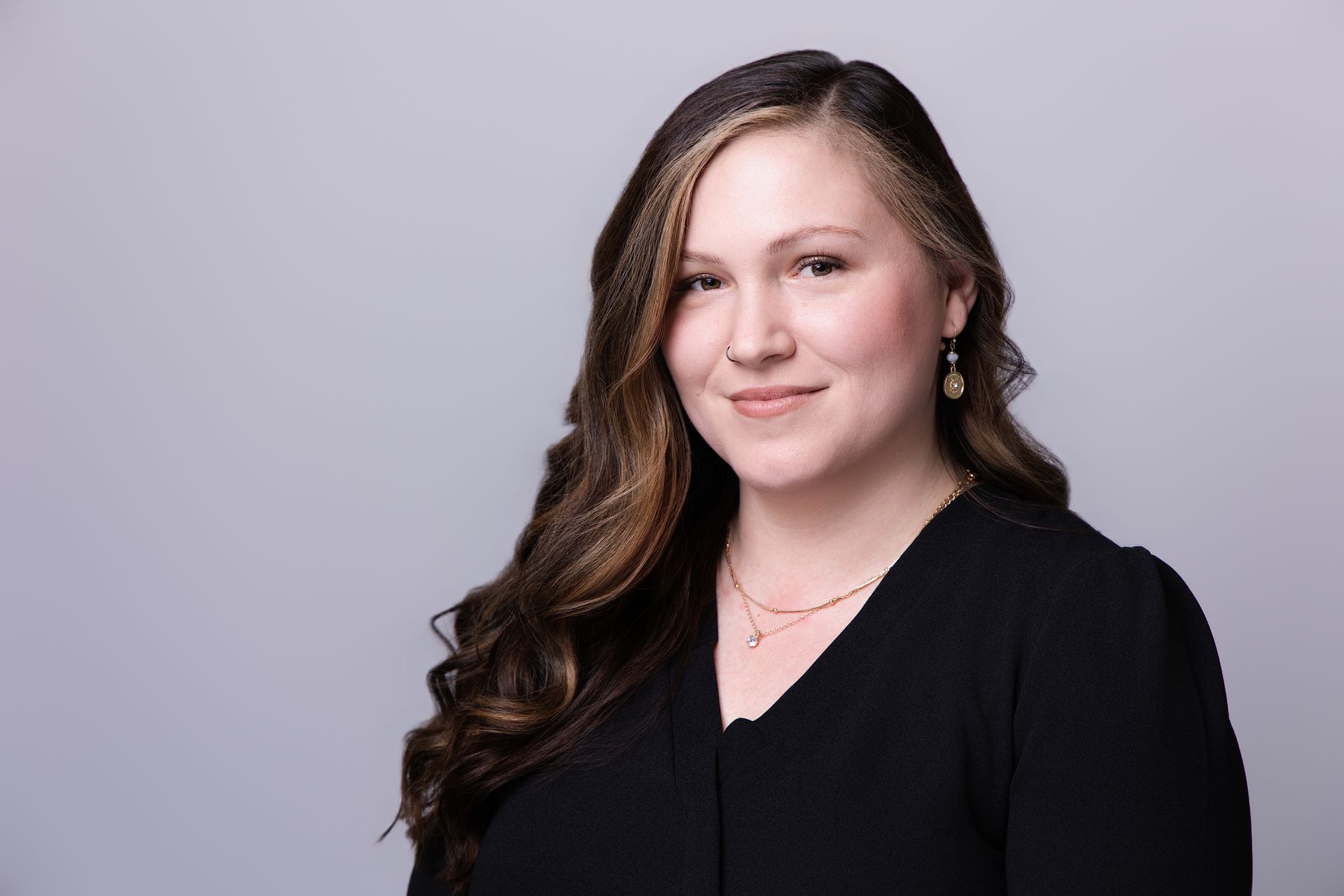 Portrait of a smiling woman in a black top against a light gray background