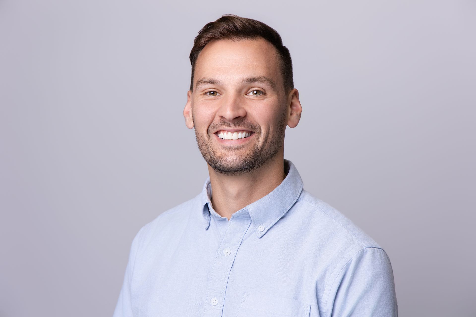 Smiling man in a light blue shirt against a light gray background