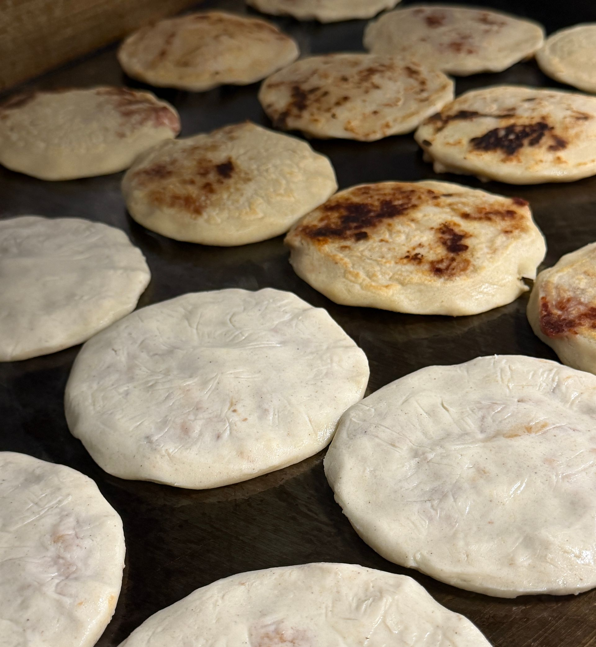 Flatbreads cooking on a griddle, some puffed and lightly browned