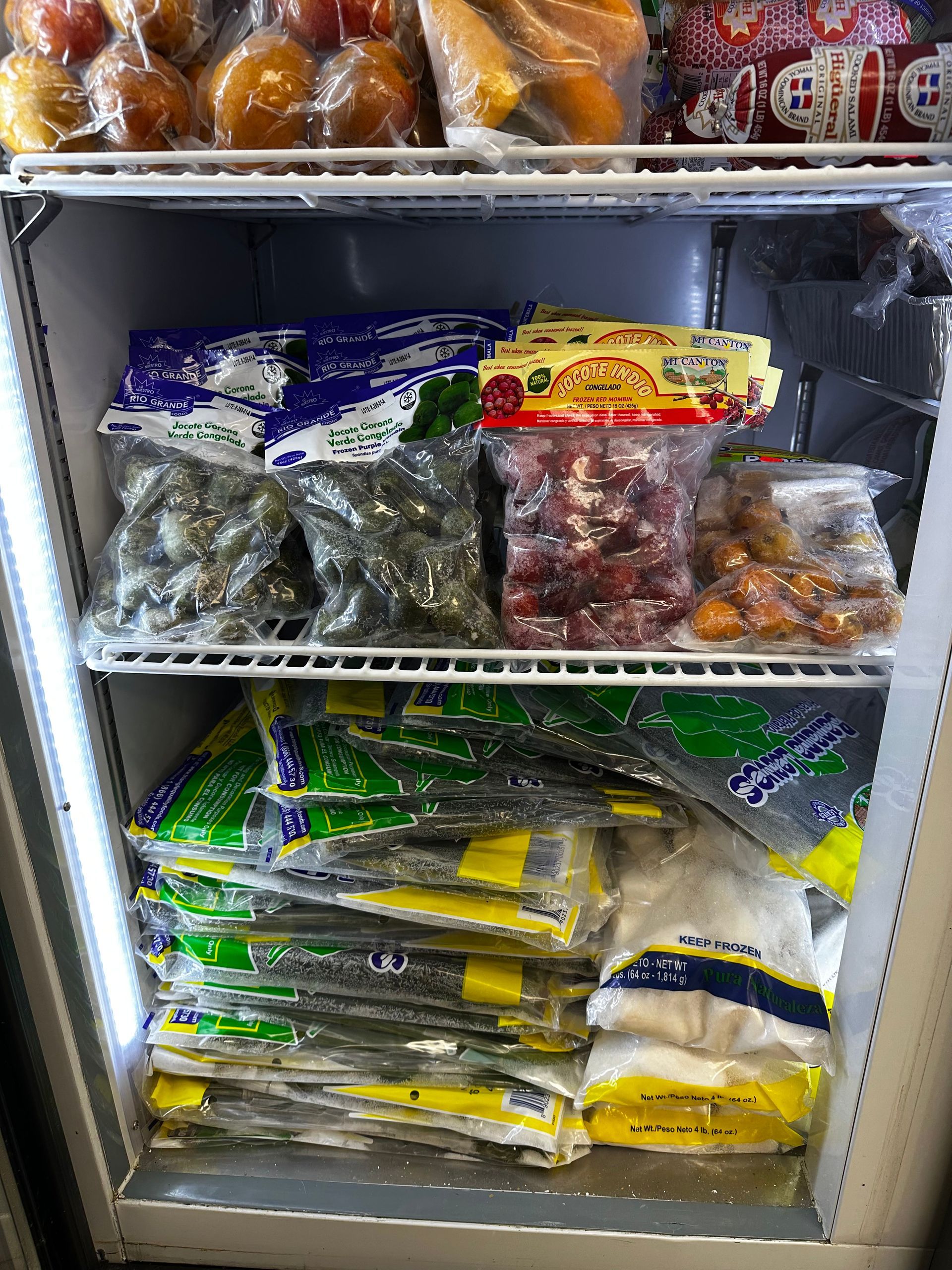 A refrigerated grocery shelf stocked with packaged vegetables, fruits, and assorted produce bags.
