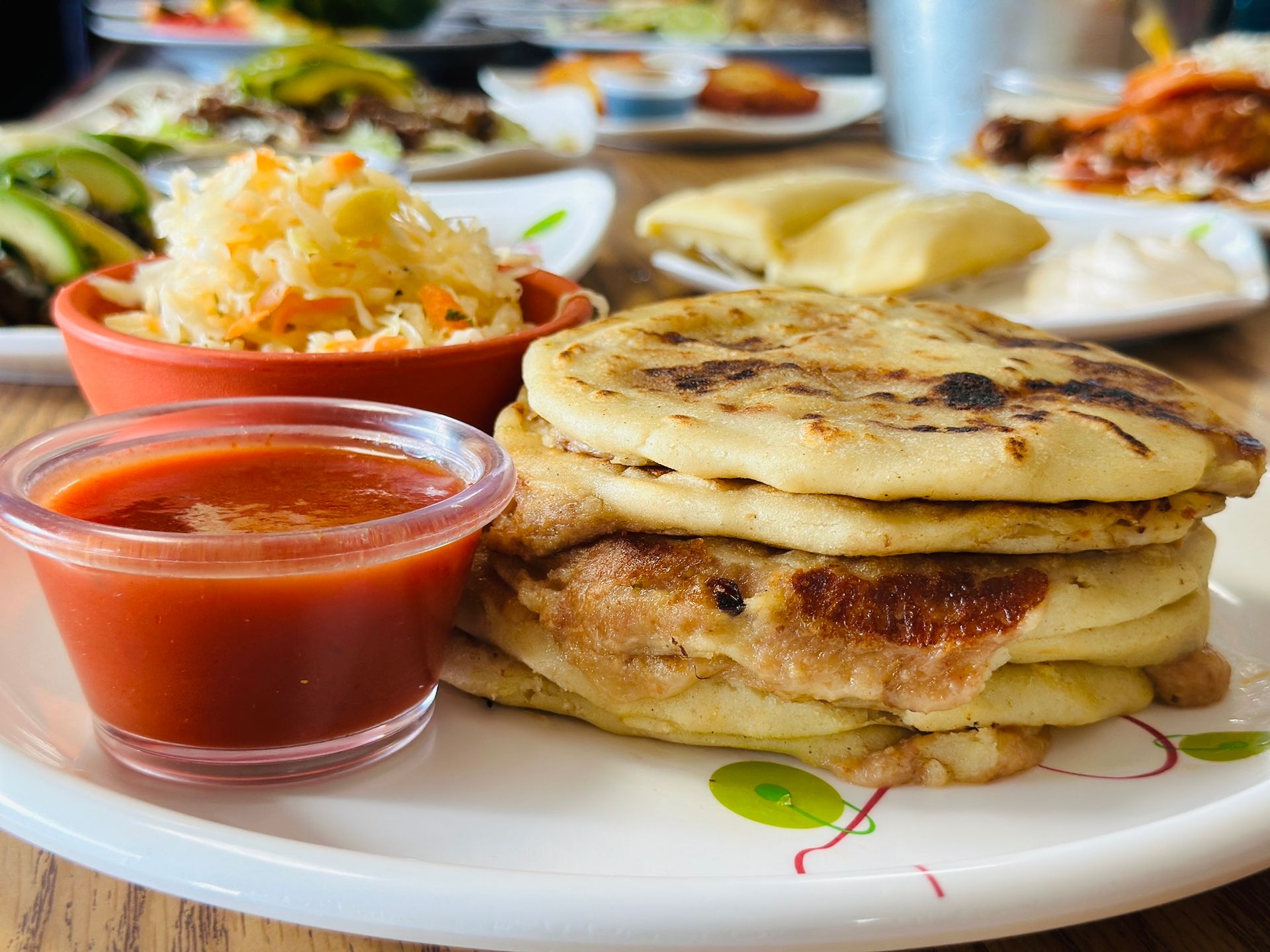 Plate of stacked pancakes with red sauce and shredded cheese on a breakfast table