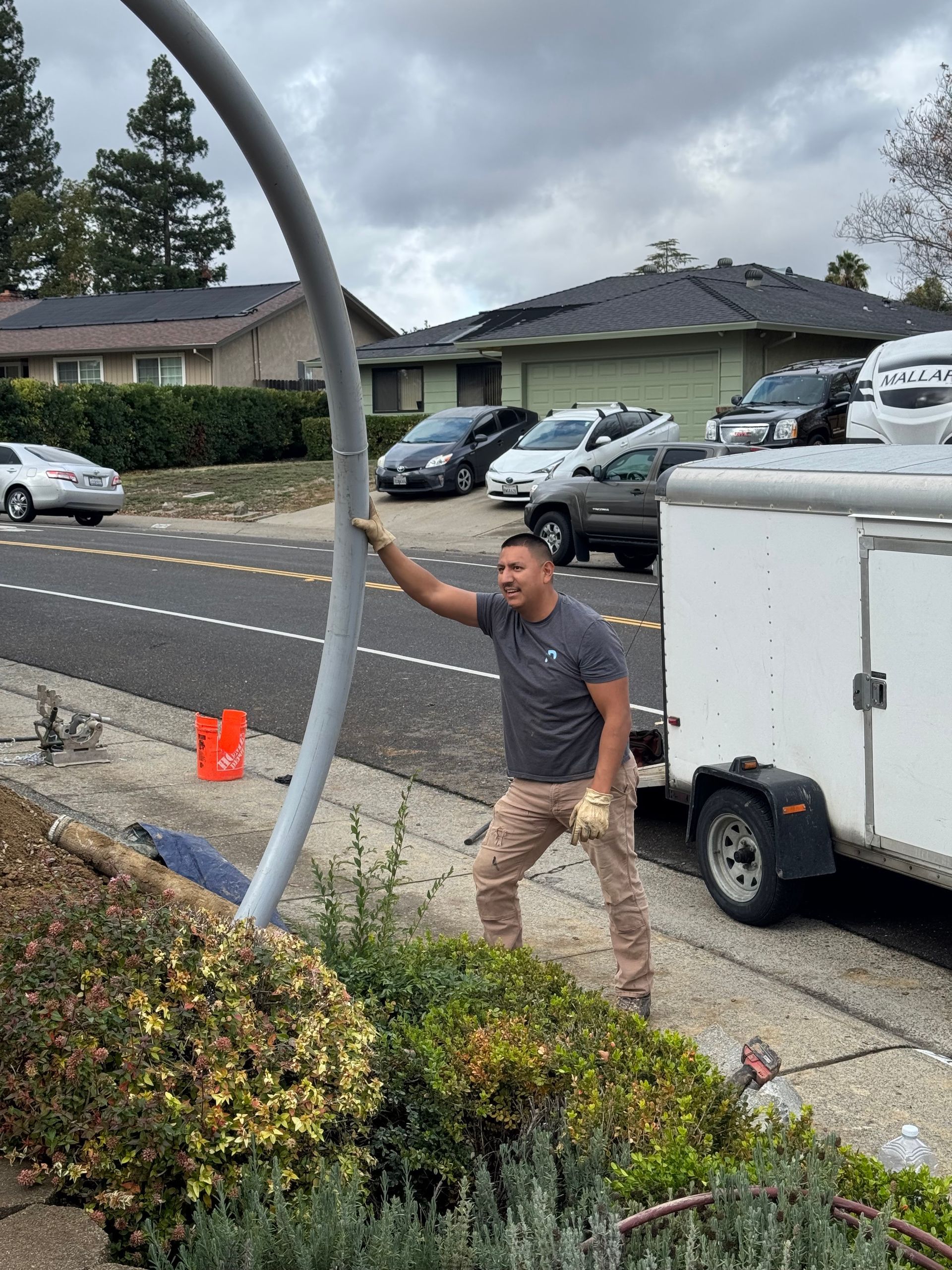 A man is standing next to a white trailer on the side of the road.