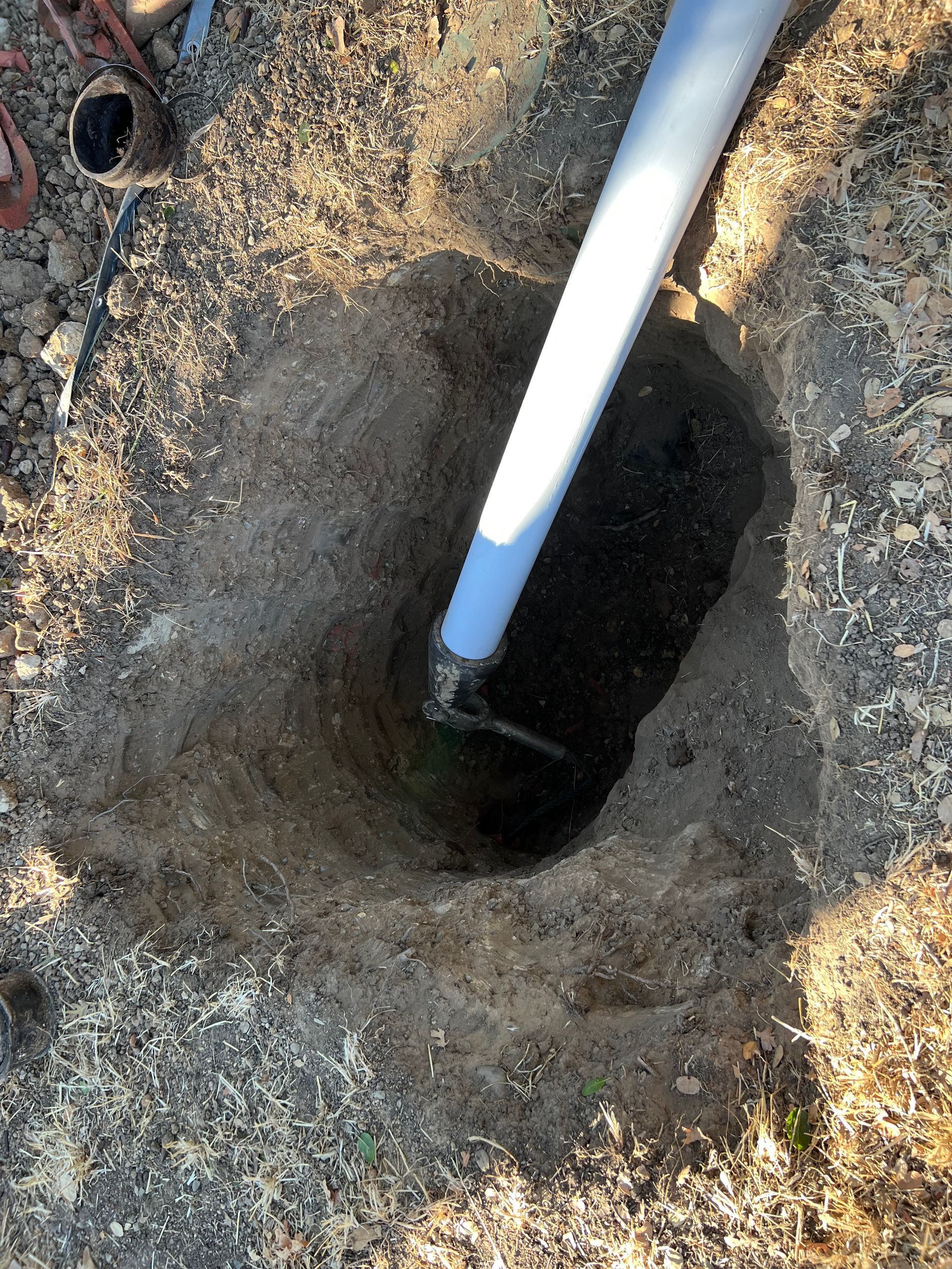 A white pipe is sticking out of a hole in the ground
