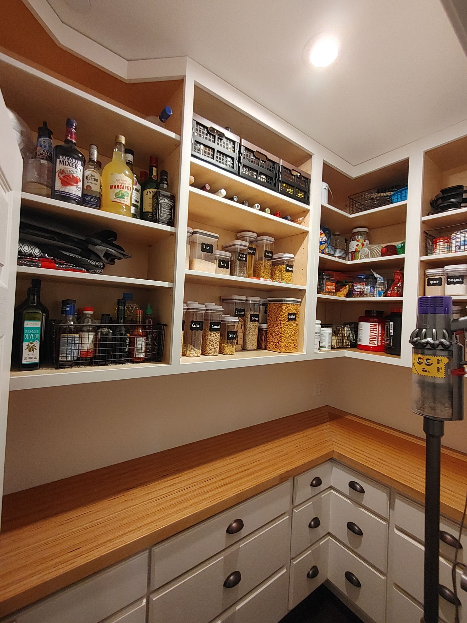 A pantry filled with lots of food and bottles of liquor.