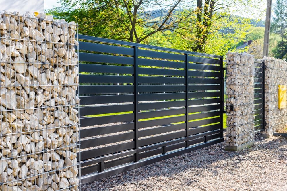 A Black Sliding Gate Is Surrounded by A Stone Wall — Fence Factory In Katherine, NT