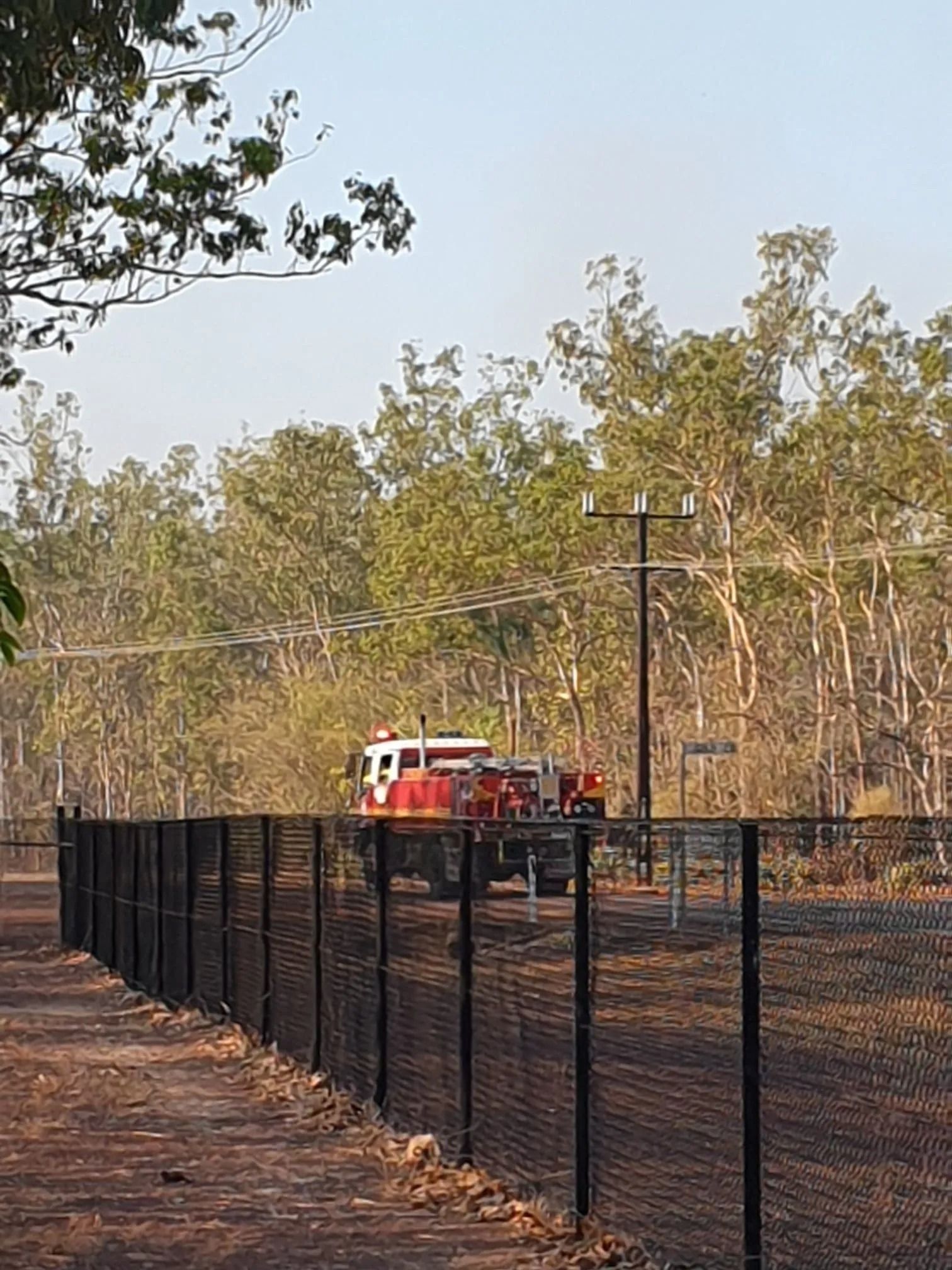 A Red Truck is Parked in a Dirt Field Behind a Fence — Fence Factory In Berrimah, NT